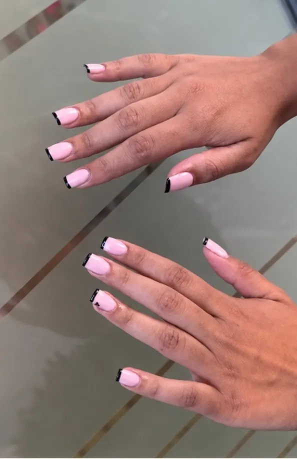 Manicure french con punta nera realizzata da IS BEAUTY, mani sul tavolo del centro