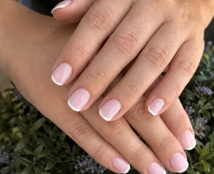 French classica con punta bianca su unghie corte, mani incrociate